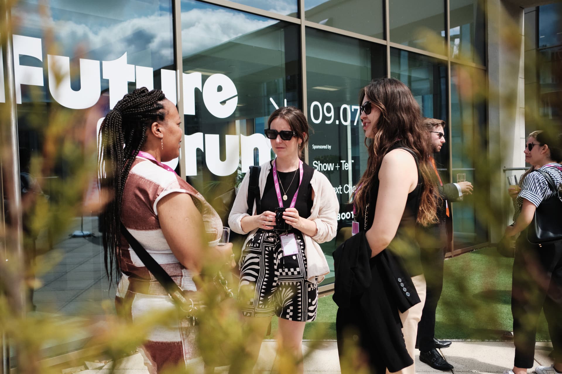 3 people chat outside on a sunny rooftop at a FutureForum event